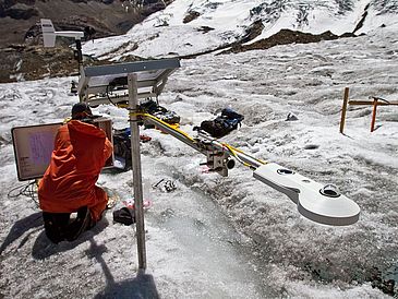 Mann mit technischen Geräten auf einem Gletscher, dden er untersucht
