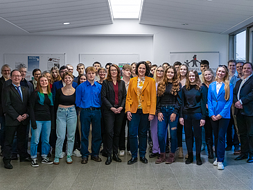 Auf dem Bild sind eine Schüler:innen-Gruppe von rund 30 Personen zu sehen. Sie stehen zusammen mit Katrin Moosdorf, Senatorin für Umwelt, Klima & Wissenschaft sowie Dr. Mandy Boehnke, Konrektorin für Internationalität, wissenschaftliche Qualifizierung und Diversität der Universität Bremen, Mandy Böhnke.