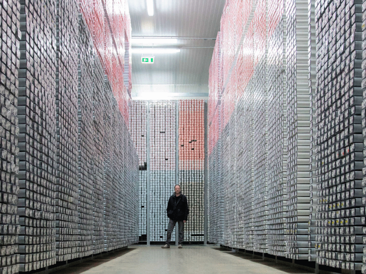 Eine Person steht im Bohrkernlager an der Universität Bremen. Sie wirkt winzig klein zwischen den vielen Meter hohen Regalen, in denen Tausende Bohrkerne lagern
