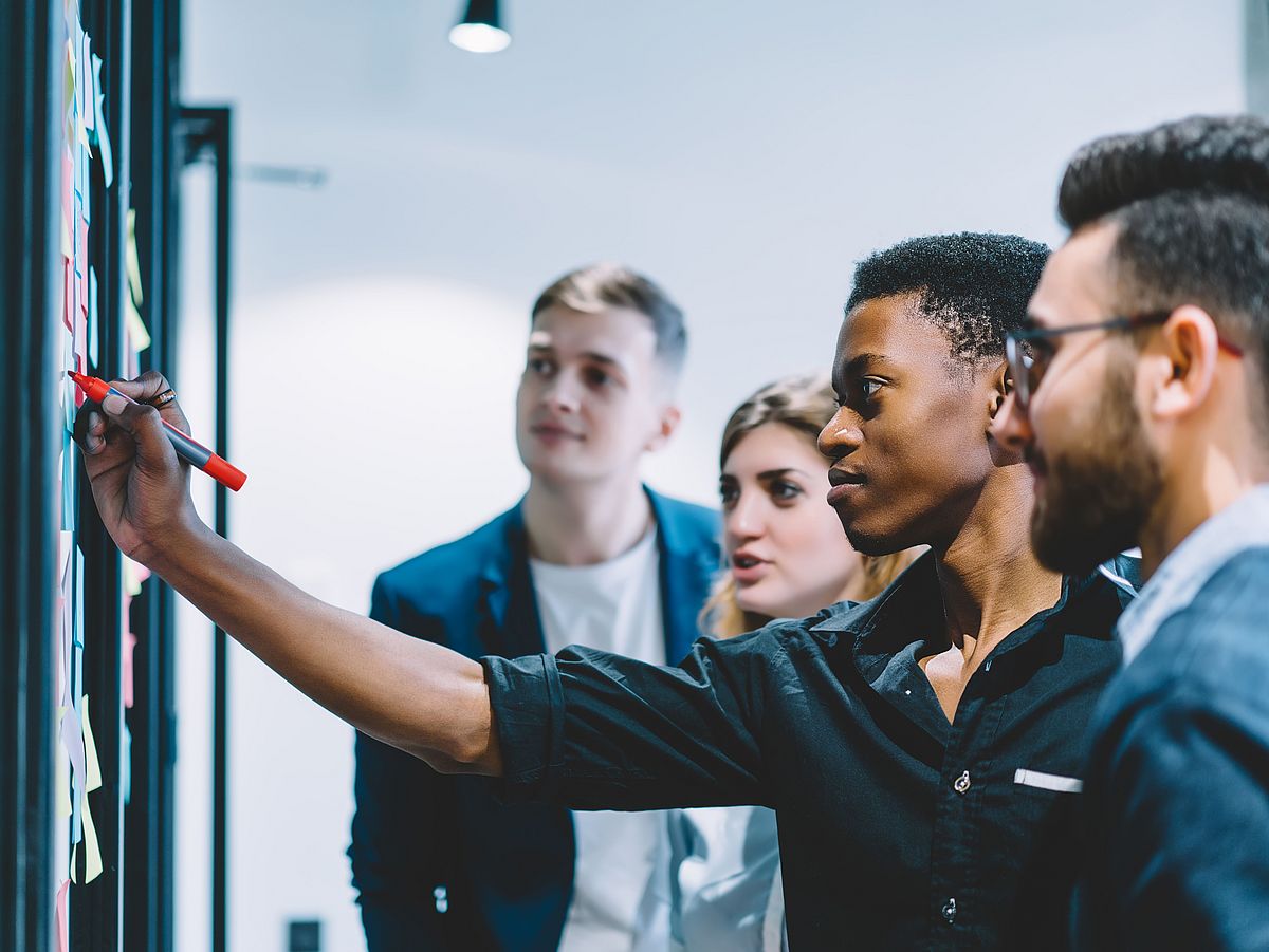 Studenten im Team an der Tafel Studenten besprechen einen Auftrag