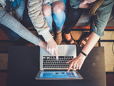 Mehrere Personen arbeiten gemeinsam an einem Laptop